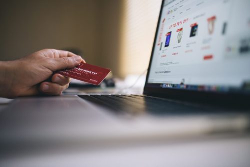 Person holding a credit card and preparing to shop online.